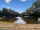 Serene view of a pond with a fountain, surrounded by lush green trees under a clear blue sky at 4406 Kendall Way, Roswell, GA 30075