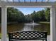 Framed view of a serene pond with a fountain, surrounded by lush trees from a seating area at 4406 Kendall Way, Roswell, GA 30075