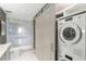 Well-equipped bathroom featuring a glass-enclosed shower, toilet, and stacked washer and dryer at 2660 Peachtree Nw Rd # 26F, Atlanta, GA 30305