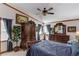 Elegant main bedroom with antique dresser, blue coverings, a ceiling fan, large plant, and an antique armoire at 5494 Princeton Oaks Ln, Sugar Hill, GA 30518
