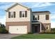 Two-story home with white siding, brick base, and a two-car garage, exuding classic charm at 8229 Coldstream Dr, Fairburn, GA 30213