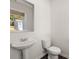 Well-lit powder room with pedestal sink and modern toilet at 8229 Coldstream Dr, Fairburn, GA 30213