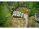 Aerial shot of a home with a green lawn, bordered by trees, featuring a long driveway and landscaped front yard at 240 Pinebrook Way, Roswell, GA 30076
