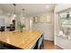 Bright kitchen with butcher block island, stainless appliances, white cabinetry, and adjacent seating area at 240 Pinebrook Way, Roswell, GA 30076