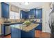 Stylish kitchen featuring navy blue cabinetry, granite countertops, and stainless steel appliances with natural lighting at 5143 Olive Branch Cir, Powder Springs, GA 30127