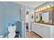 A bathroom with a toilet and double sink vanity with an oversized mirror, well lit with modern vanity lights at 4342 Richmond Nw Pl, Acworth, GA 30101