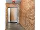 Hallway featuring brick walls, a door, and an 'EXIT' sign above the doorway at 490 Marietta Nw St # 105, Atlanta, GA 30313