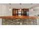 Basement bar with a stone facade, wooden countertop, pendant lighting, and custom cabinets at 500 Poplar Creek Xing, Canton, GA 30114