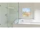 Bright bathroom featuring a large glass door shower, and a jetted tub under a large window with backyard view at 500 Poplar Creek Xing, Canton, GA 30114