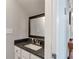 Bathroom featuring granite countertop, white cabinets, and framed mirror at 241 Quail Run, Roswell, GA 30076