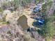 Aerial view of a home near a pond, along with other outbuildings on lush, tree-filled acreage at 1768 Hood Rd, Dacula, GA 30019