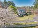 Charming white farmhouse featuring a covered front porch, lush greenery, and flowering trees at 1768 Hood Rd, Dacula, GA 30019