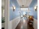 Hallway leading to a room with blue walls, hardwood floors, and sconce lighting at 1768 Hood Rd, Dacula, GA 30019