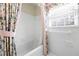 Bright bathroom featuring a white tiled tub/shower and a window with floral curtains and pink trim at 5269 Wyntercreek Dr, Atlanta, GA 30338