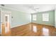A spacious bedroom featuring hardwood floors, light green walls, three windows, and a ceiling fan at 5269 Wyntercreek Dr, Atlanta, GA 30338