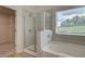 Modern bathroom featuring a glass-enclosed shower, a separate soaking tub, and a large window, creating a bright and airy space at 1079 Georgian Point Dr, Lawrenceville, GA 30045