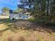 A view of the backyard and back of the home with a small patio visible, surrounded by trees and grass at 6406 Laurel Post Dr, Lithonia, GA 30058