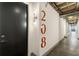 Hallway with modern lighting, exposed pipes, and visible unit number, ensuring easy navigation at 1065 United Ave # 208, Atlanta, GA 30316