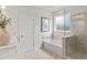 Bright bathroom featuring a soaking tub and tiled glass enclosed shower with neutral color palette at 1613 Caldwell Bend Ln, Dacula, GA 30019