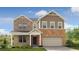 Two story home with a brick and stone facade, covered front porch, and manicured lawn at 1613 Caldwell Bend Ln, Dacula, GA 30019
