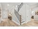 Open hallway featuring a staircase with black metal railings and light hardwood floors at 1613 Caldwell Bend Ln, Dacula, GA 30019