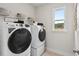 Well-equipped laundry room with modern washer, dryer, shelving, and a window offering natural light at 1613 Caldwell Bend Ln, Dacula, GA 30019