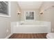 Bathroom features a soaking tub surrounded with white tile, and wood floor at 2938 Parkwood Rd, Snellville, GA 30039