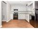 Galley style kitchen with white cabinets, granite countertops, black appliances, and wood floors at 2938 Parkwood Rd, Snellville, GA 30039