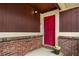 Close-up of a vibrant red front door with brick accents and stylish exterior lighting at 49 Country Ct, Alpharetta, GA 30005