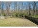 An open, grassy backyard with wood fencing overlooks the natural forest scenery at 7324 Drake Ave, Lithonia, GA 30058