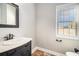 Powder room featuring a marble-top vanity, decorative mirror, and a window for natural light at 1092 Shumard Ln, Mcdonough, GA 30252