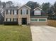 Two-story home with tan siding, a black front door, and a well-maintained front lawn at 2469 Briar Knoll Rd, Lithonia, GA 30058