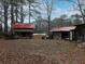 Exterior view of several weathered log cabins with red roofs surrounded by trees at 3844 Oglesby Rd, Powder Springs, GA 30127
