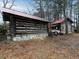 Exterior view of a vintage log cabin with stone accents and tractor at 3844 Oglesby Rd, Powder Springs, GA 30127