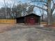 Exterior view of a barn garage with brown wood, red doors, and surrounding trees at 3844 Oglesby Rd, Powder Springs, GA 30127