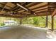 Large carport with wooden beam ceiling, lighting, and a view of the wooded surroundings at 5369 Blue Grass Ln, Sugar Hill, GA 30518