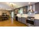 Modern kitchen featuring gray cabinetry, stainless steel appliances, white backsplash, and hardwood floors open to dining area at 5369 Blue Grass Ln, Sugar Hill, GA 30518