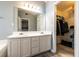 Bathroom with double vanity, large mirror, and walk in closet with shelving at 7617 Lakemoor Dr, Riverdale, GA 30296