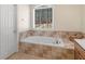 Bathroom with a soaking tub under a large window, complemented by a white door and earth-tone tiles at 355 Parker Rd, Covington, GA 30014