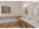 Relaxing bathroom with a soaking tub under a large window, complemented by double vanity and earth-tone tiles at 355 Parker Rd, Covington, GA 30014