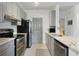 Bright kitchen features stainless steel appliances, grey cabinets, stone countertops and tiled backsplash at 7104 Woodland Ln, Alpharetta, GA 30009