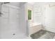 Bright bathroom featuring a tub, separate shower, and a large window overlooking nature at 4630 Smokestone Dr, Douglasville, GA 30135