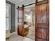 Bathroom featuring sliding barn doors, stone floors, and luxurious soaking tub at 4852 Jacobs Cove Pt, Buford, GA 30519