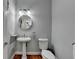 Charming powder room with a pedestal sink, decorative mirror, and warm lighting at 4852 Jacobs Cove Pt, Buford, GA 30519
