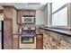 Compact kitchen features wooden cabinets, stainless steel appliances, and a stone accent wall near the window at 4852 Jacobs Cove Pt, Buford, GA 30519