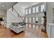 Open living room with hardwood floors, a stone fireplace, large windows and a staircase leading to the upper level at 4852 Jacobs Cove Pt, Buford, GA 30519