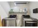 Modern laundry room featuring stainless steel washer and dryer with overhead shelf storage and convenient power outlet at 1198 Olmsted Park Rd, Decatur, GA 30033