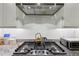 Close-up of gas stovetop with stainless steel vent hood and granite counters at 1198 Olmsted Park Rd, Decatur, GA 30033