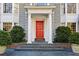 Close up view of a home's entrance with white pillars, a red front door, and manicured landscaping at 2820 Andrews Nw Dr, Atlanta, GA 30305