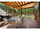 A covered wooden deck with a table, chairs, and grill overlooking the backyard and mature trees at 3076 Harris Mill Ct, Duluth, GA 30096